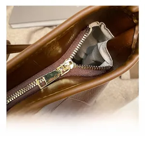 Detailed close-up of golden zipper hardware and quilted leather on brown tote bag