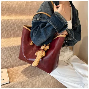 Detail of burgundy leather tote bag with diamond stitching and contrast trim with bear charm