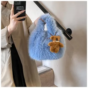 Detail of light blue faux fur tote bag with a cute brown teddy bear plush pendant