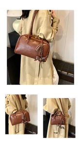 Detail of vintage brown leather bowling bag with cute chocolate and puppy charms