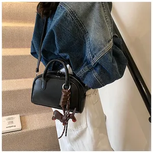 Close-up of a retro black bowling handbag with cute charms, worn with a denim jacket