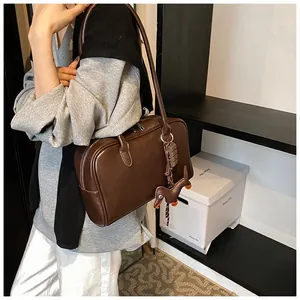 Detail view of dark brown polished leather bowling bag with creative hanging charms