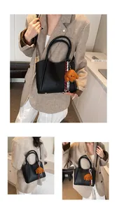 Detail of black lychee grain leather bucket bag with puppy charm and crossbody strap