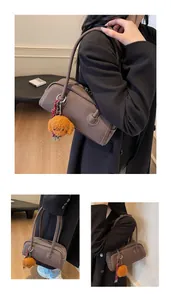 Brown Boston underarm bag with embossed text and a cute orange plush bear charm detail
