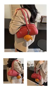 Detailed view of red leather pillow bag with white stitching and puppy charm