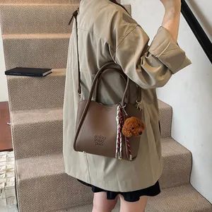 Brown litchi grain vintage handbag with teddy charm and adjustable crossbody strap