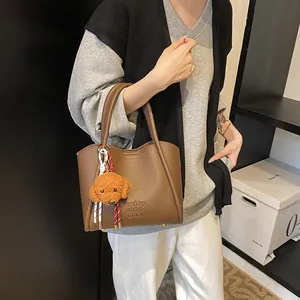 Brown lychee leather bucket bag with dog charm and Enjoy Chce text for women