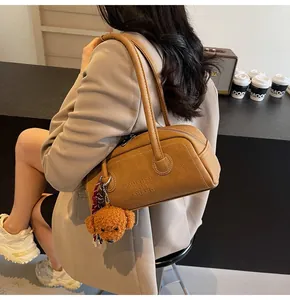Detailed close-up of brown leather boston bag with a cute teddy bear plush charm