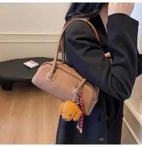 Detailed view of brown litchi leather bag with brand embossing and cute dog charm