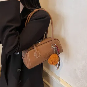 Vintage brown leather underarm bag with teddy charm on chic black blazer background