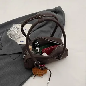 Deep brown litchi pattern leather shoulder bag with plush bear charm on a gray blazer