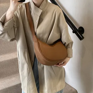 Sac bandoulière demi-lune marron avec motif litchi porté par un mannequin femme