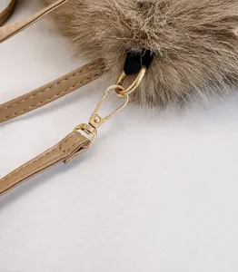 Detailed close-up of golden metal buckle and brown faux fur texture on handbag