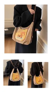 Détail du sac hobo en daim kaki avec patch chat et bandoulière réglable en cuir
