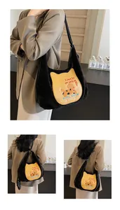 Détails de broderie chat et texture peluche sur un sac à bandoulière noir chic