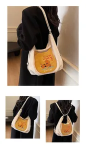 Détail d'un sac hobo beige avec patch chat cartoon et bandoulière réglable en métal