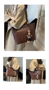 Détail du grand sac cabas vintage marron en cuir avec breloque lapin et texte doré