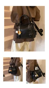 Detail van de zwarte Boston-tas van mat leer met een sportieve bedel als accessoire