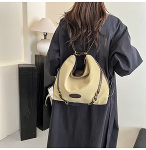 Detail of hobo style nylon shoulder bag with brown leather straps and metallic rings