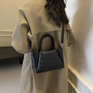 Modische schwarze Leder-Eimertasche mit Webmuster und Doppelgriffen am Model gezeigt