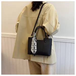 Vue détaillée du sac seau noir motif litchi avec foulard pied-de-poule porté par mannequin