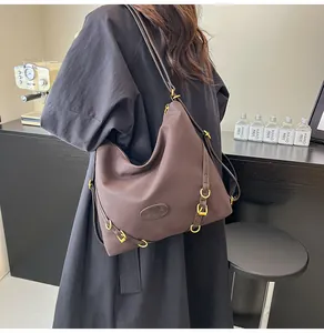 Detailed shot of dark brown large nylon tote bag with gold buckle on a model in trench coat