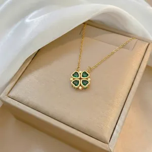 Foldable gold clover necklace with heart shaped green crystals on white satin