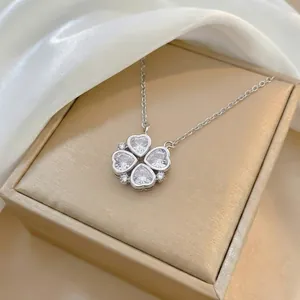 Macro view of silver four-leaf clover pendant with heart-shaped crystals on satin lining