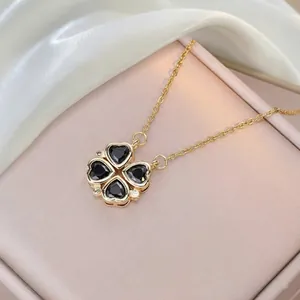 Detail of clover heart necklace with black gemstones and white crystals on white silk