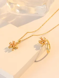 Macro detail of gold-plated flower jewelry set with pink zircons on a white platform