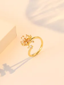 Detail of a golden flower ring with sparkling zircon petals on a minimal warm background