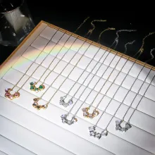 Detalle de colgantes de herradura con esmeraldas y circonitas en cadenas de oro y plata