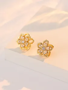 Vue détaillée de boucles d'oreilles fleur dorées avec zircons sur un socle blanc pur