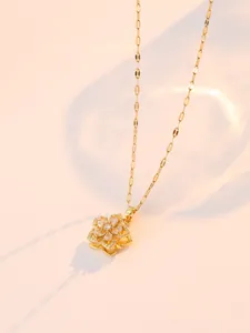 Macro d'un pendentif fleur dorée avec pétales rotatifs et pierres de zircon incrustées
