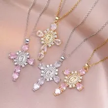 Detalle de colgantes de cruz con iconos de María y circonitas sobre seda rosa