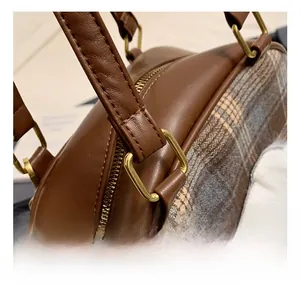 Detail of vintage gold hardware and stitching on a brown checkered tote bag