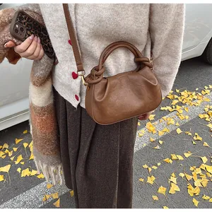 Détail du sac en cuir plissé marron avec texte embossé et bandoulière réglable