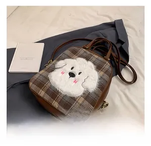 Detail of checkered tote bag featuring a cute plush dog embroidery and brown leather straps