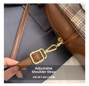 Detail view of adjustable shoulder strap with gold-tone hardware on brown plaid tote
