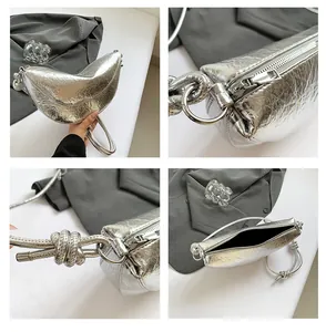 Detailweergave van de zilveren halvemaanvormige tas met metallic textuur en knoopriem