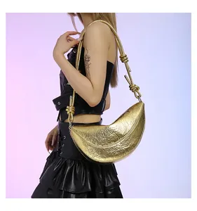 Detail van gouden halvemaantas met metallic plooien en geknoopte riem op model