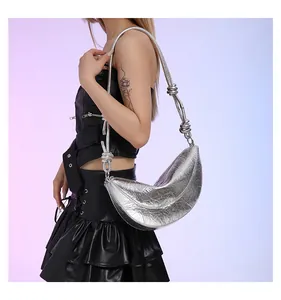 Detail van zilveren halve maan tas met knoopriem en geplooide metallic textuur