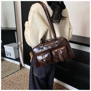 Detail view of a vintage dark brown leather shoulder bag featuring two buckled pockets