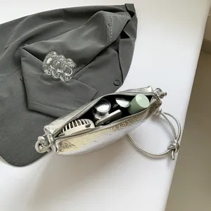Zilveren halve maan tas met metallic textuur en zicht op de praktische binnenkant