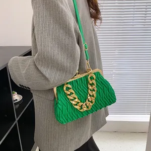 Green pleated cloud bag with chunky gold chain and leather strap on stylish model