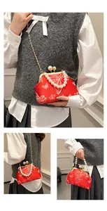 Detalle de bordado floral en bolso retro rojo con cierre de perla y cadena dorada