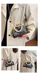 Detalle de bordado de flores y mariposas en bolso vintage con asa de perlas