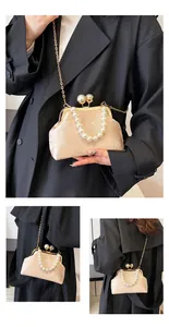 Detalle del bordado floral y asa de perlas en el bolso de concha color champán