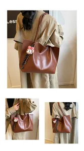 Detail of dark brown leather tote bag showing vertical stitching and plush charm decoration