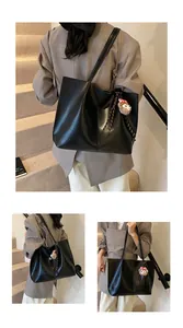 Close-up of black retro tote bag featuring a cute plush bear charm and woven cord detail